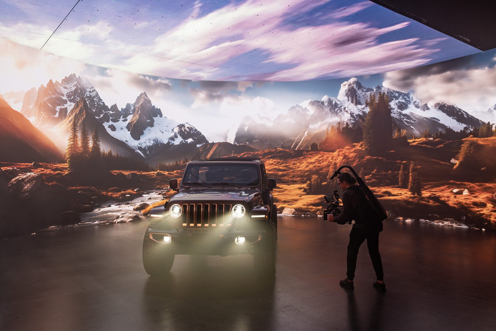Cameron Melcher filming a Jeep on an LED volume stage, snow-capped mountains on the screen behind it