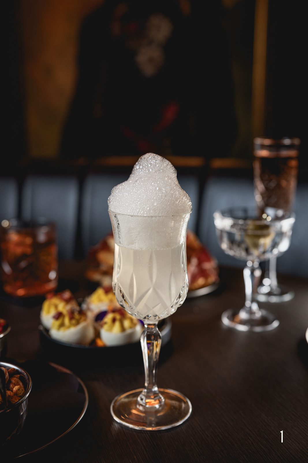 Frozen cocktail with towering foam beside a martini in the dim bar at Jekyll in Hyde Park, Tampa