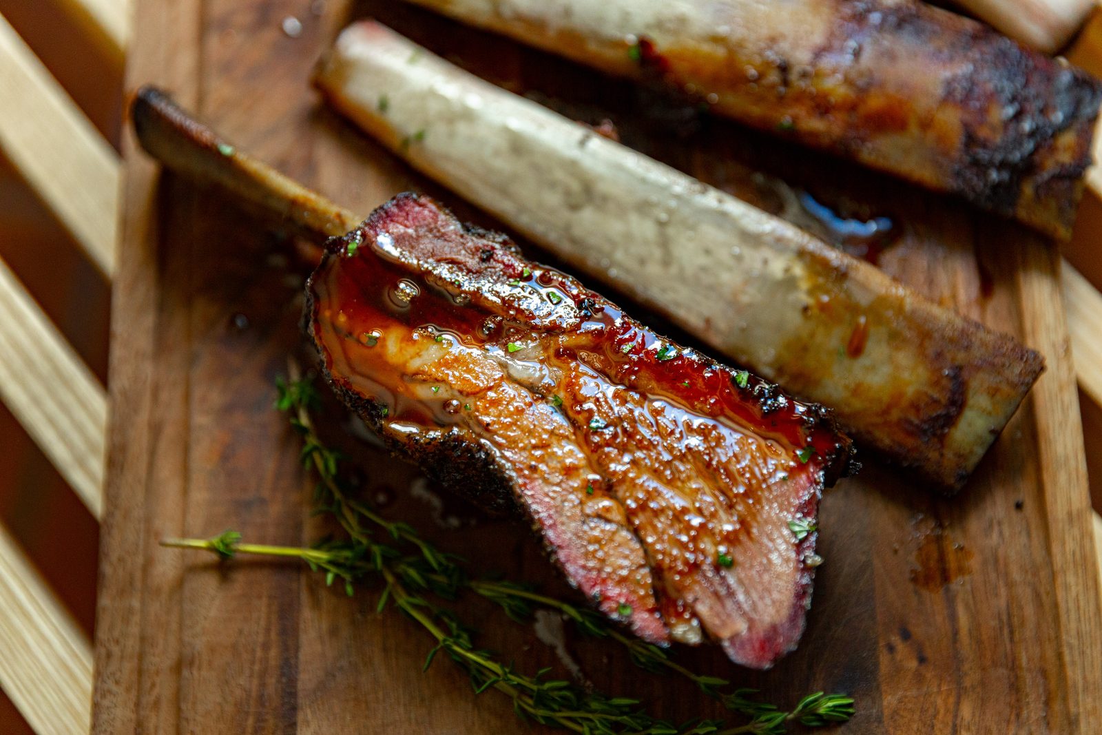 Glazed HeartBrand beef short rib on a wood board with fresh thyme