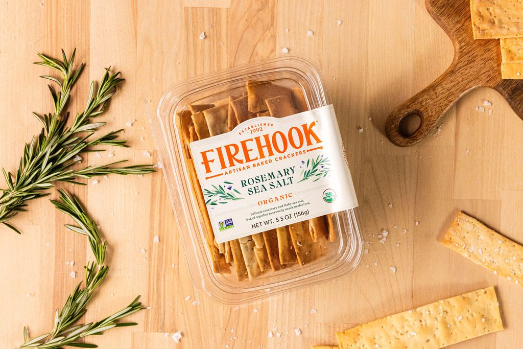 Firehook rosemary sea salt crackers with fresh rosemary and crumbs on a wood board